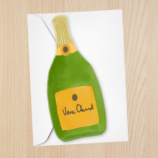 A white greeting card featuring a hand-drawn green champagne bottle with a yellow label reading 'Vive Chant' and a white envelope, placed on a light wood background.
